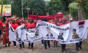 Manifestation de l'Union des peuples du Cameroun avec une banderole où il y a les visages des différents militant·e·s de l'UPC.